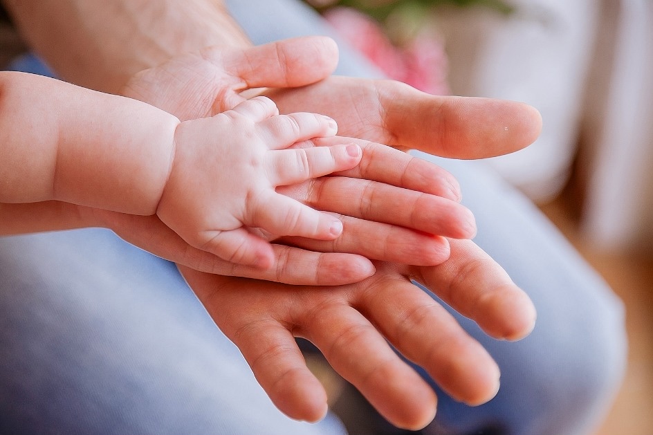 A closeup of a family's hands with a dad, mom and baby