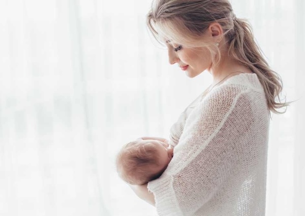 Mother standing and holding a baby at breast