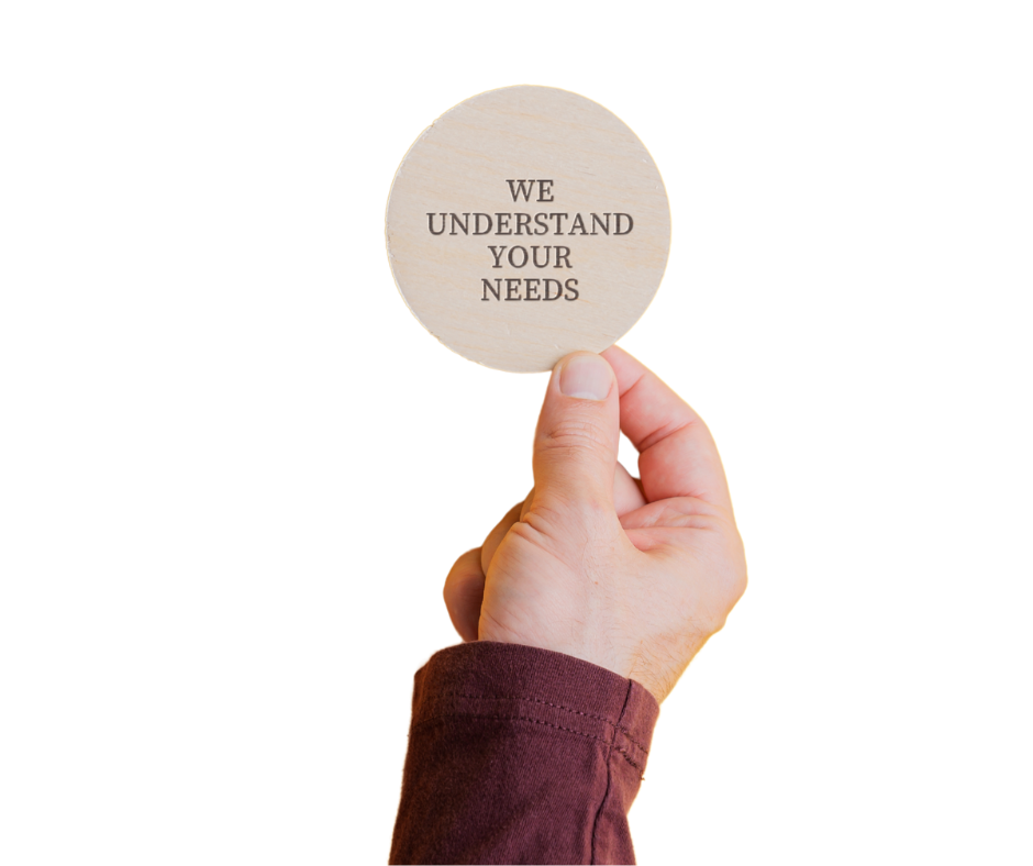 A hand holding a round paper sign with the words "we understand your needs"