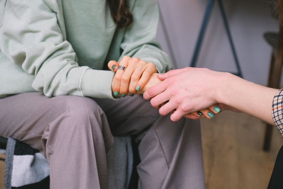 A girl holding another girls hand supportively as in a counseling session
